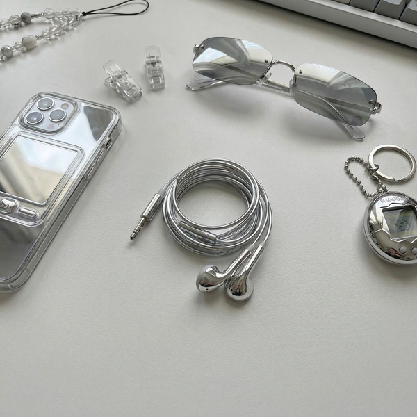 Chrome earbuds flat lay with phone and sunglasses